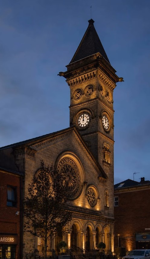 The old church building and illuminated clock tower at dusk