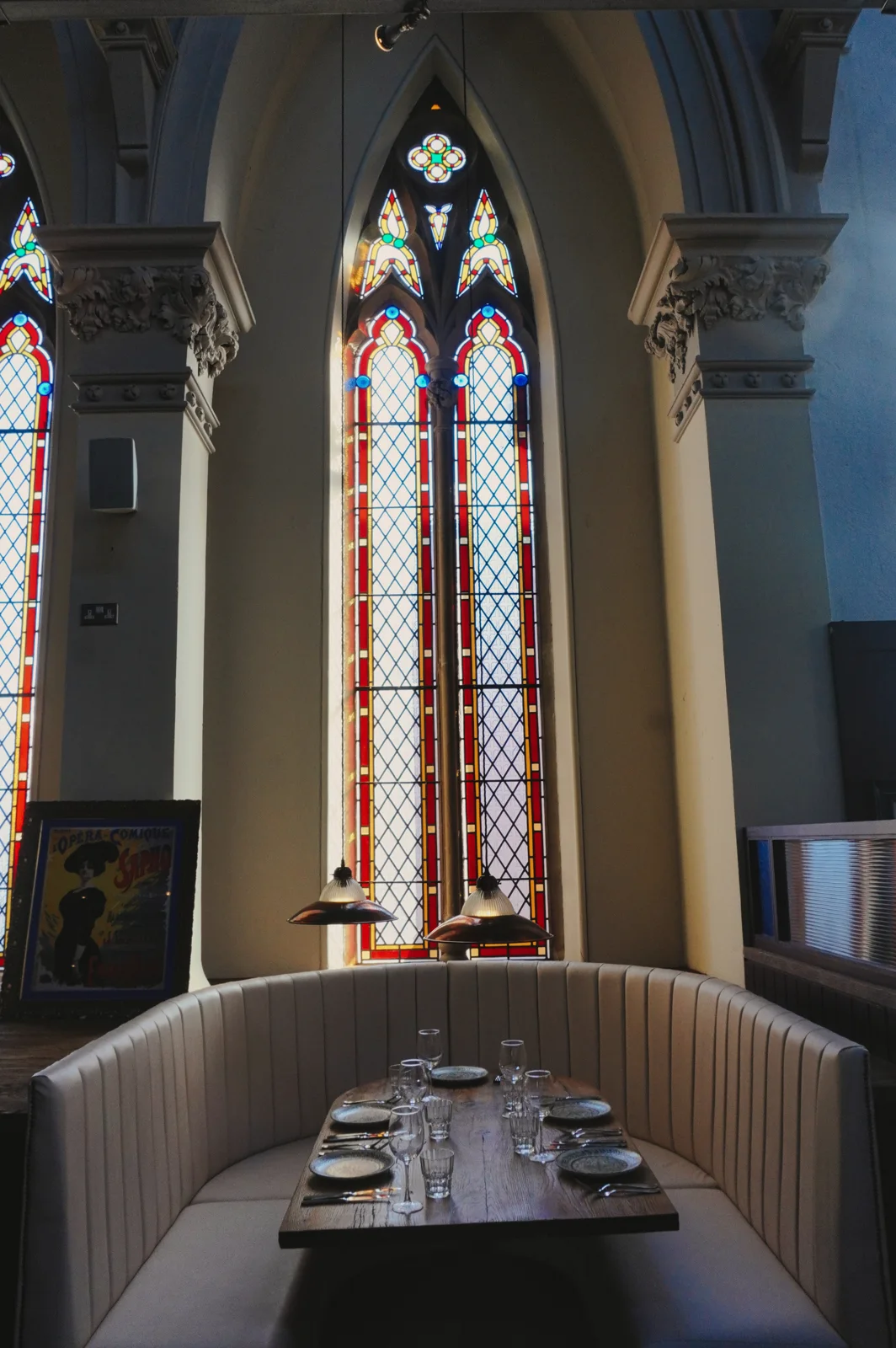 A dining booth beneath a tall stained-glass window