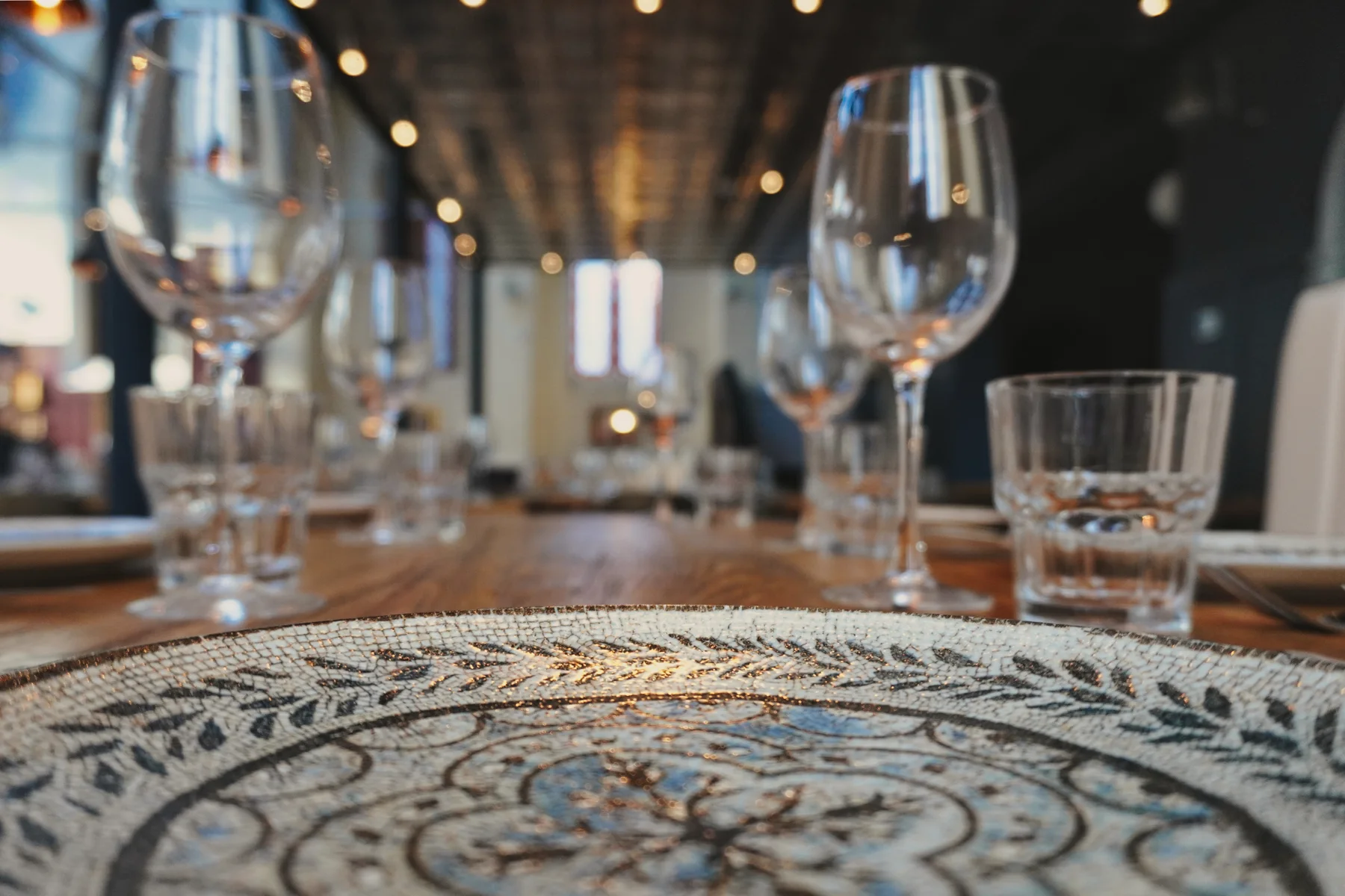 Patterned crockery and glassware on a wooden dining table