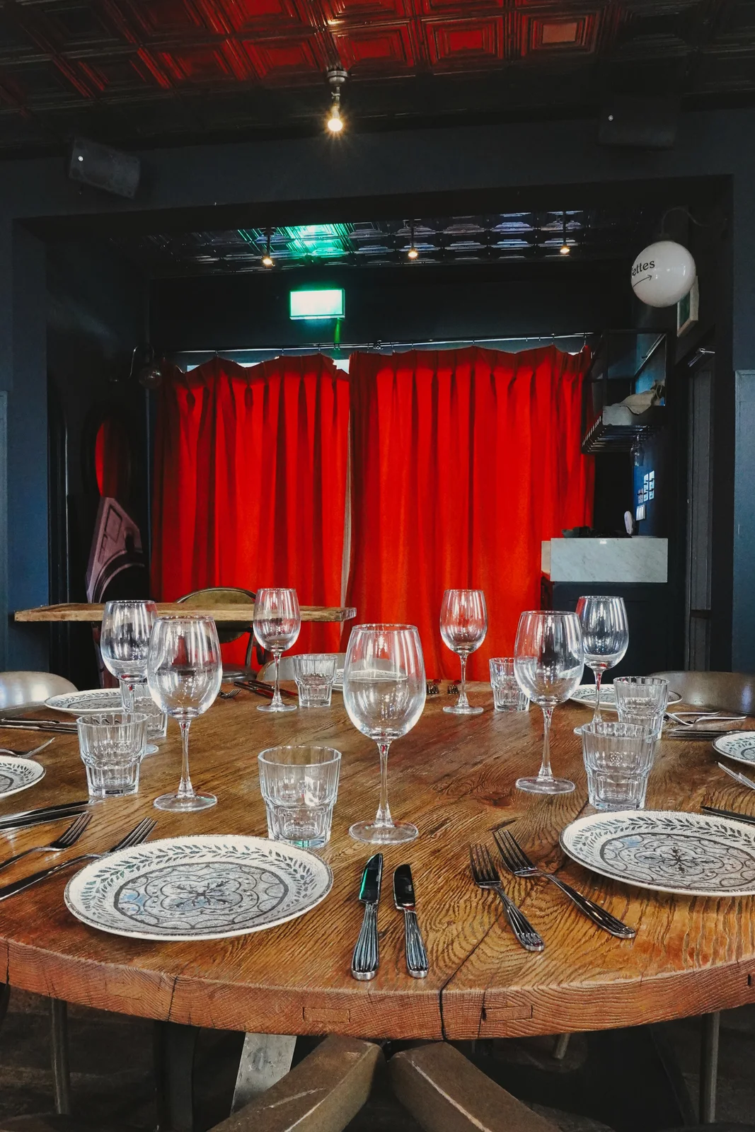 A table set for guests beside red curtains