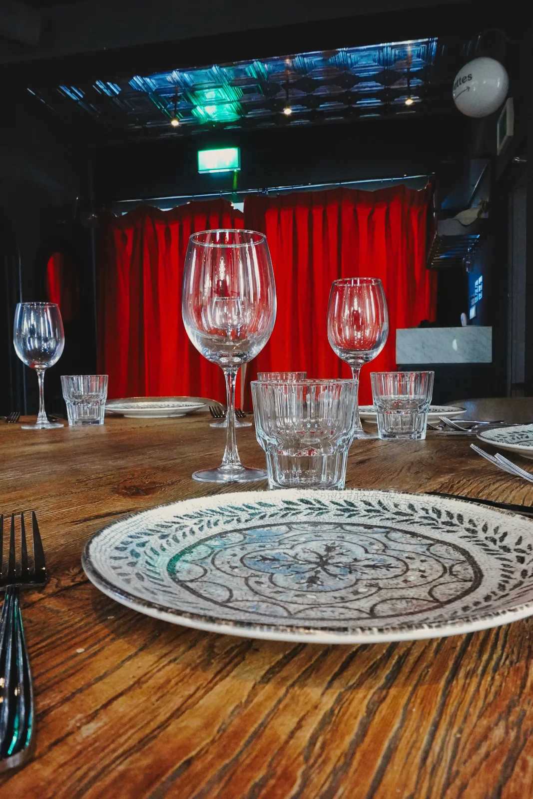 A table set for guests beside red curtains