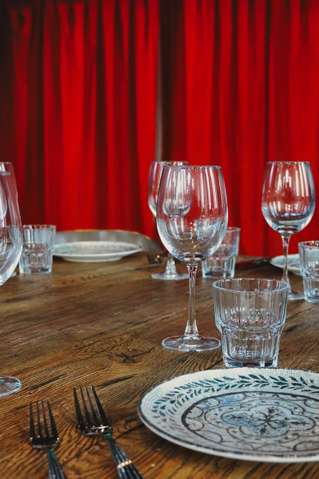 A table set for guests beside red curtains