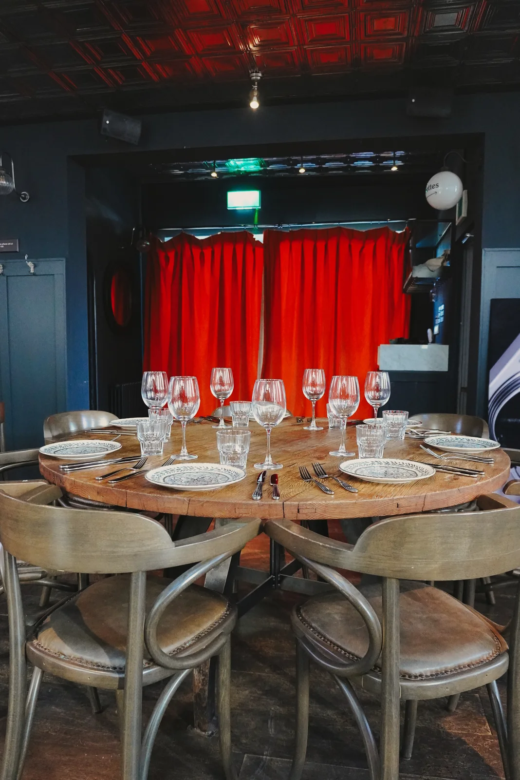 A table set for guests beside red curtains