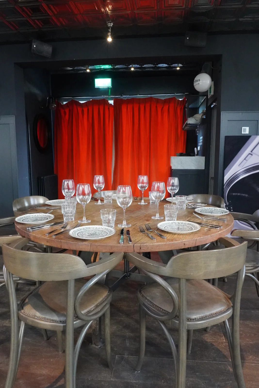 A table set for guests beside red curtains