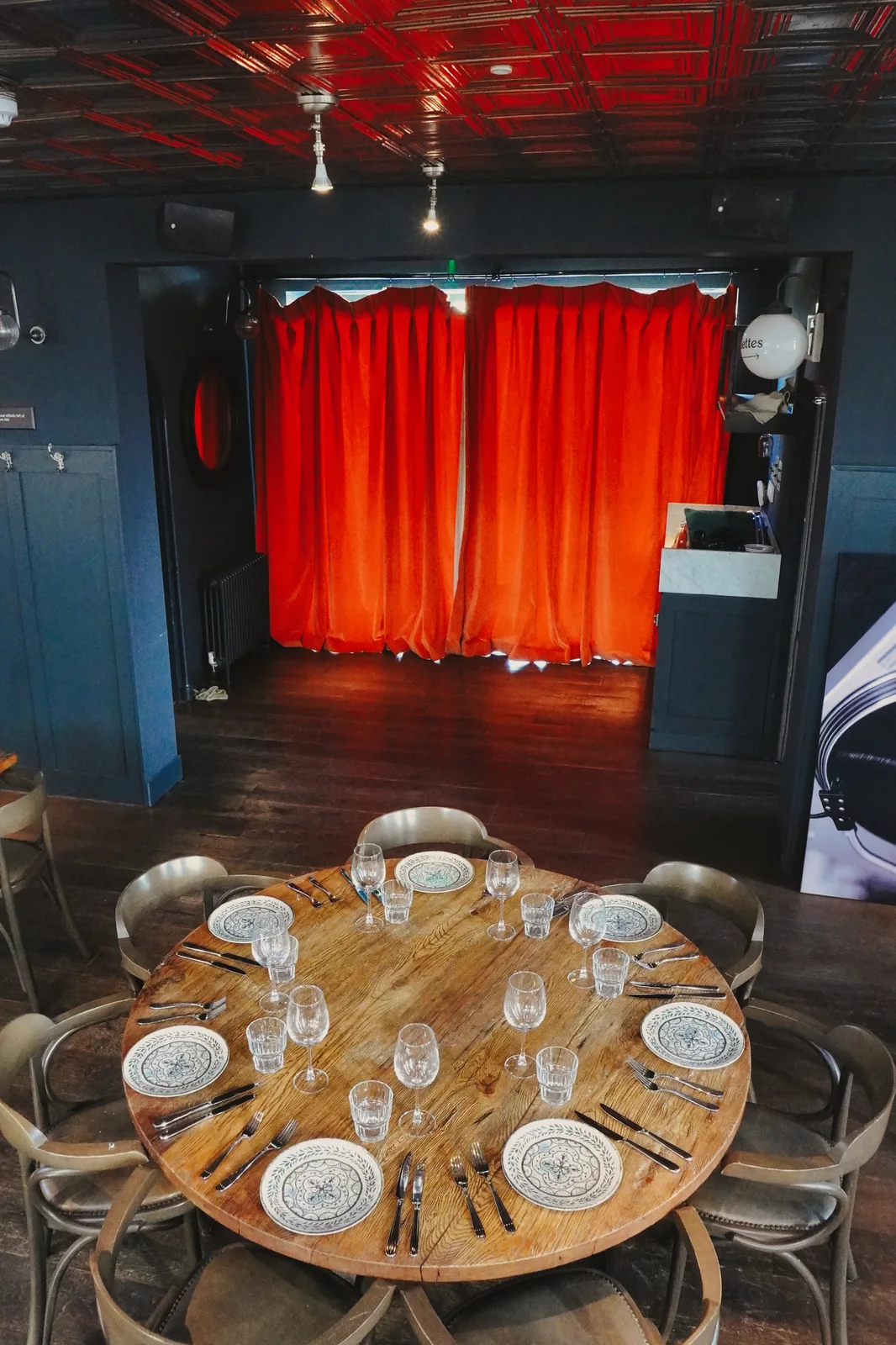 A table set for guests beside red curtains