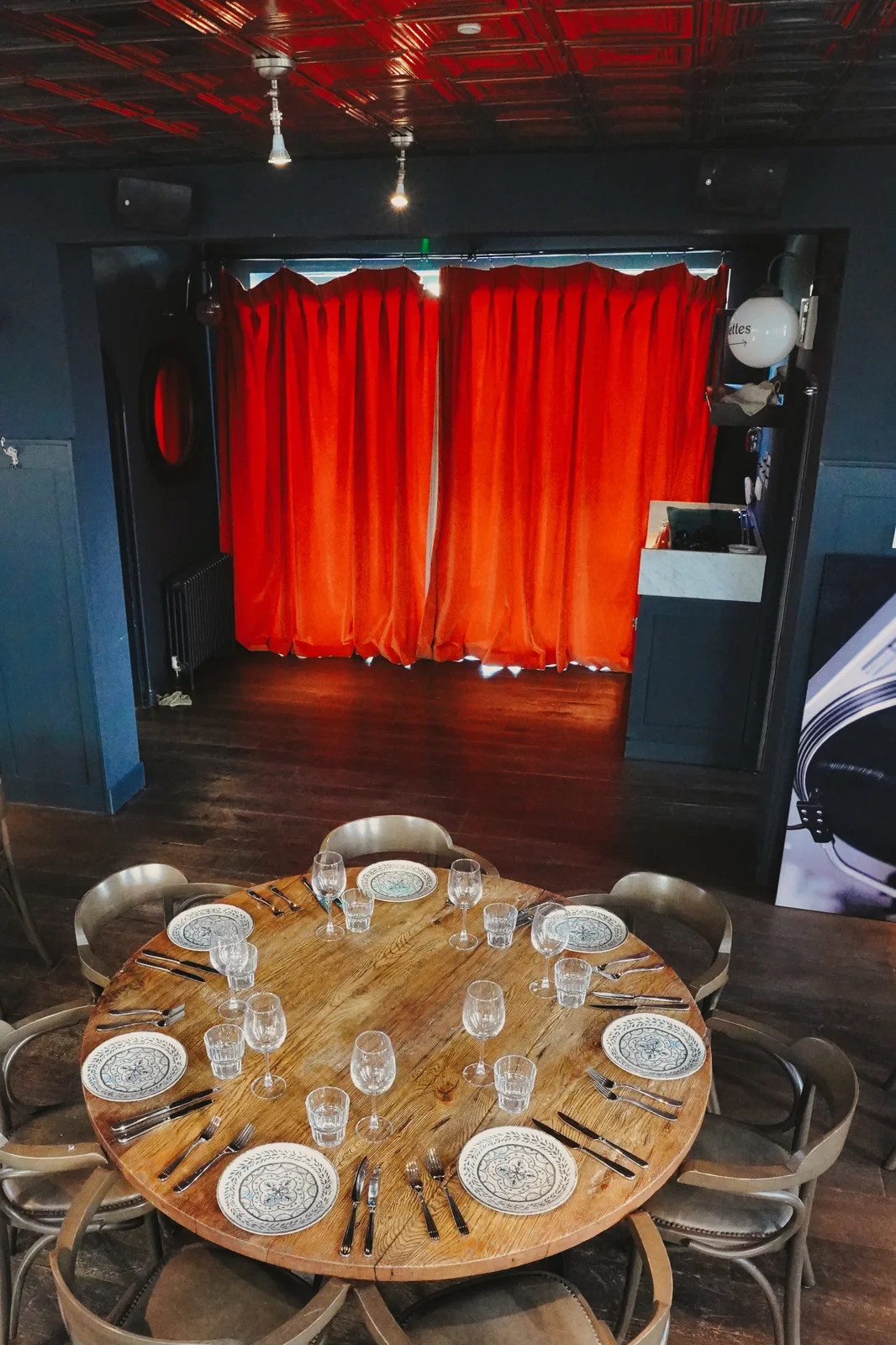 A table set for guests beside red curtains