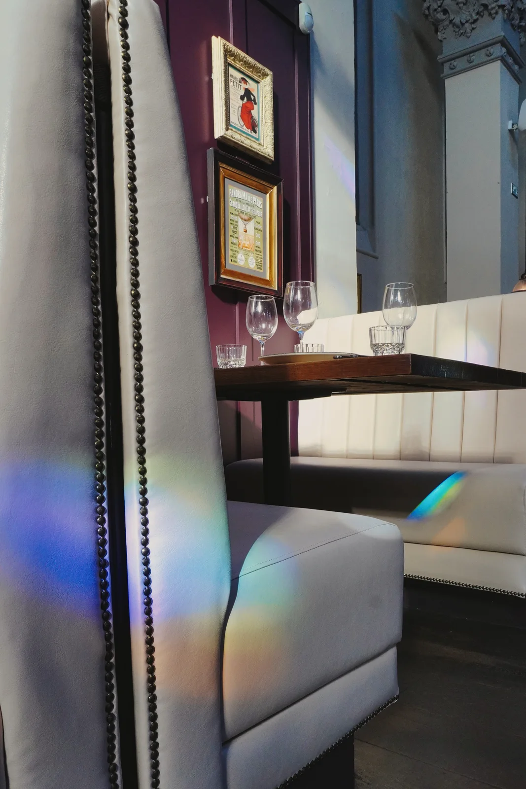 Coloured window light across cream seating and dining tables