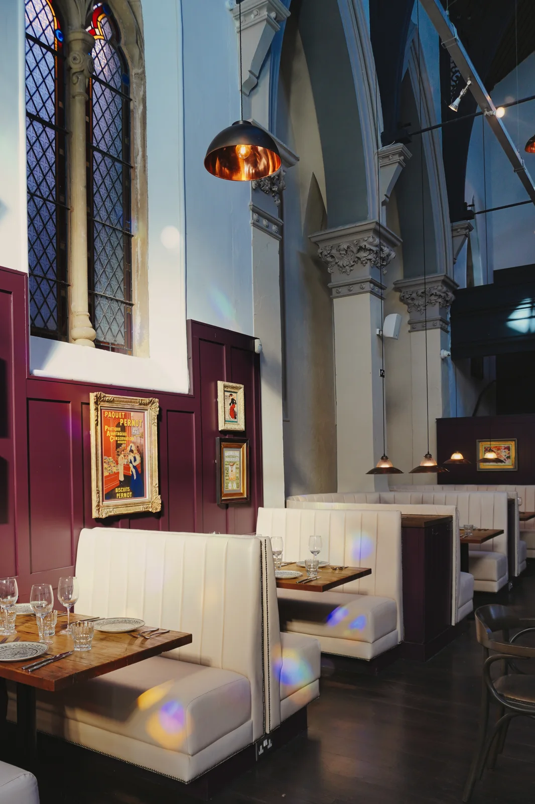 Coloured window light across cream seating and dining tables