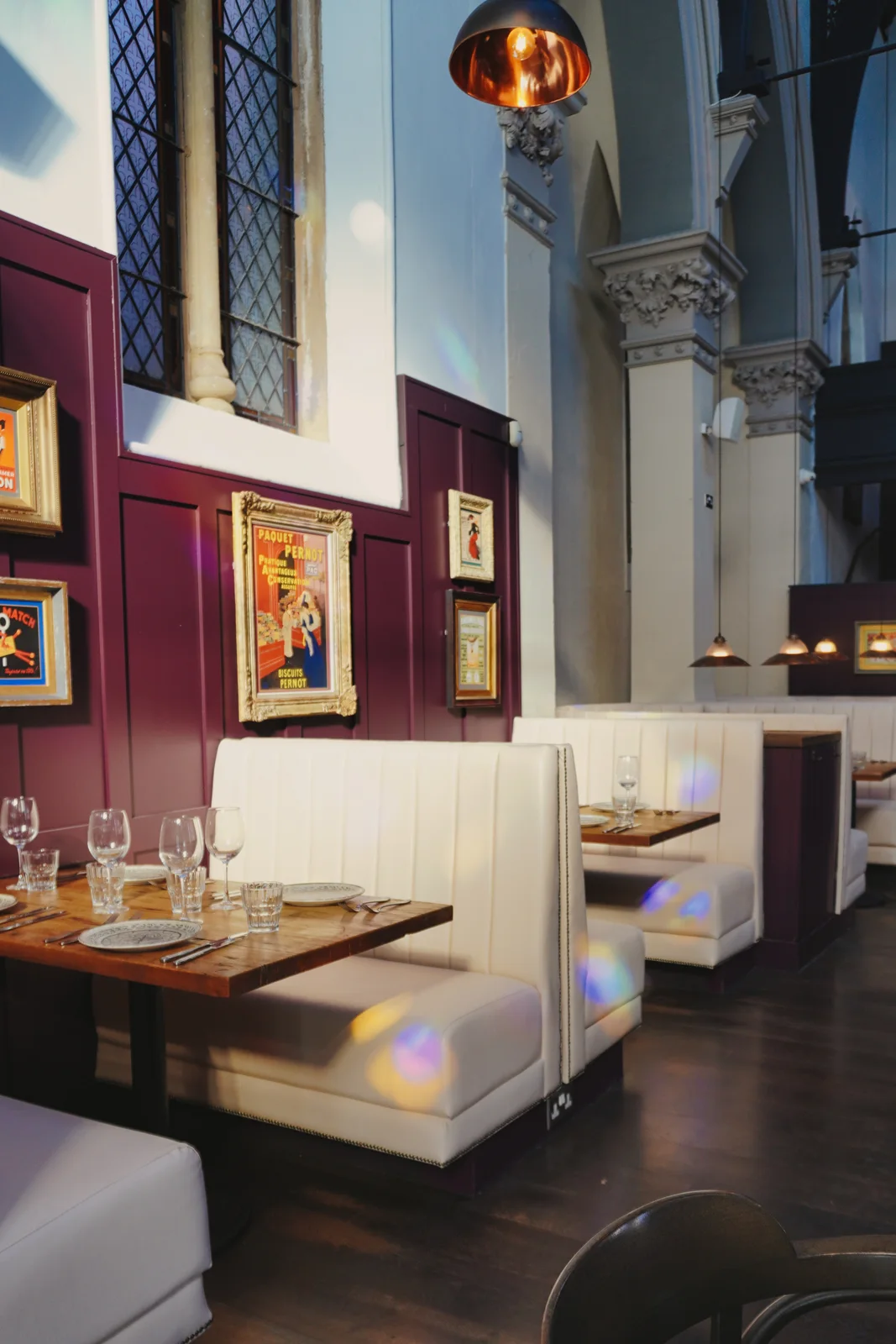 Coloured window light across cream seating and dining tables