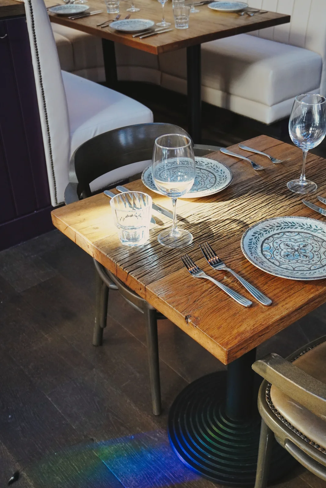 Coloured window light across cream seating and dining tables