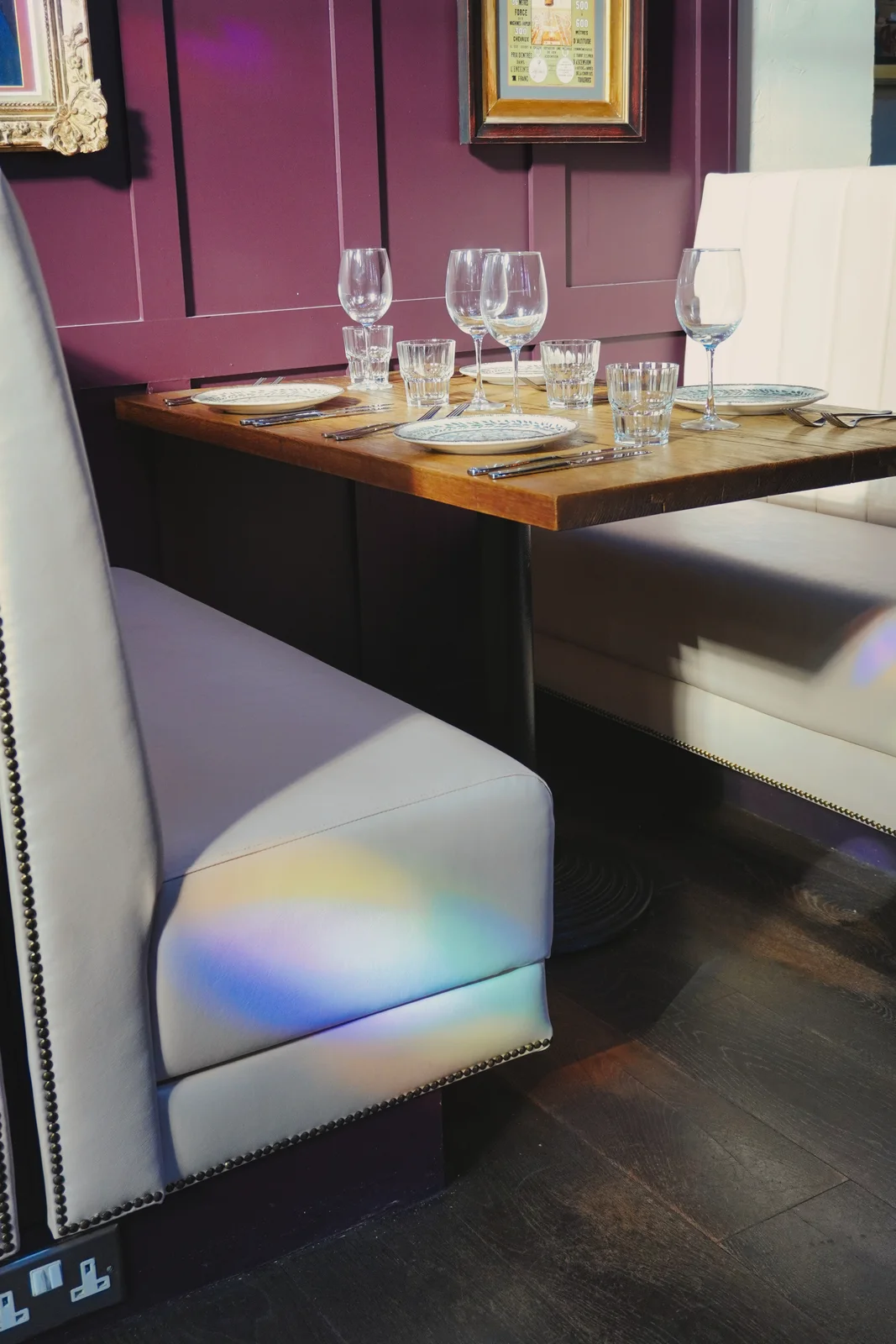Coloured window light across cream seating and dining tables