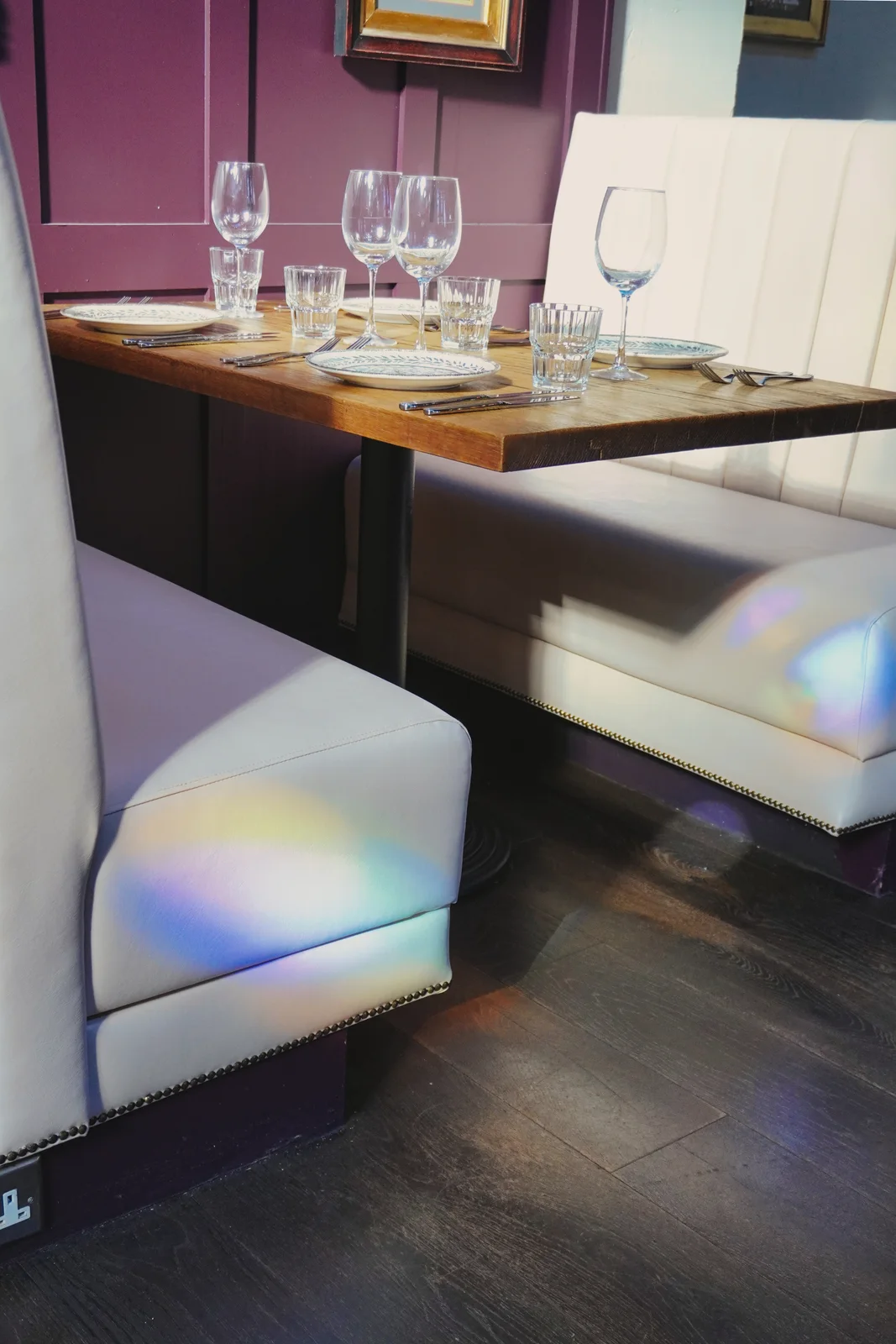 Coloured window light across cream seating and dining tables
