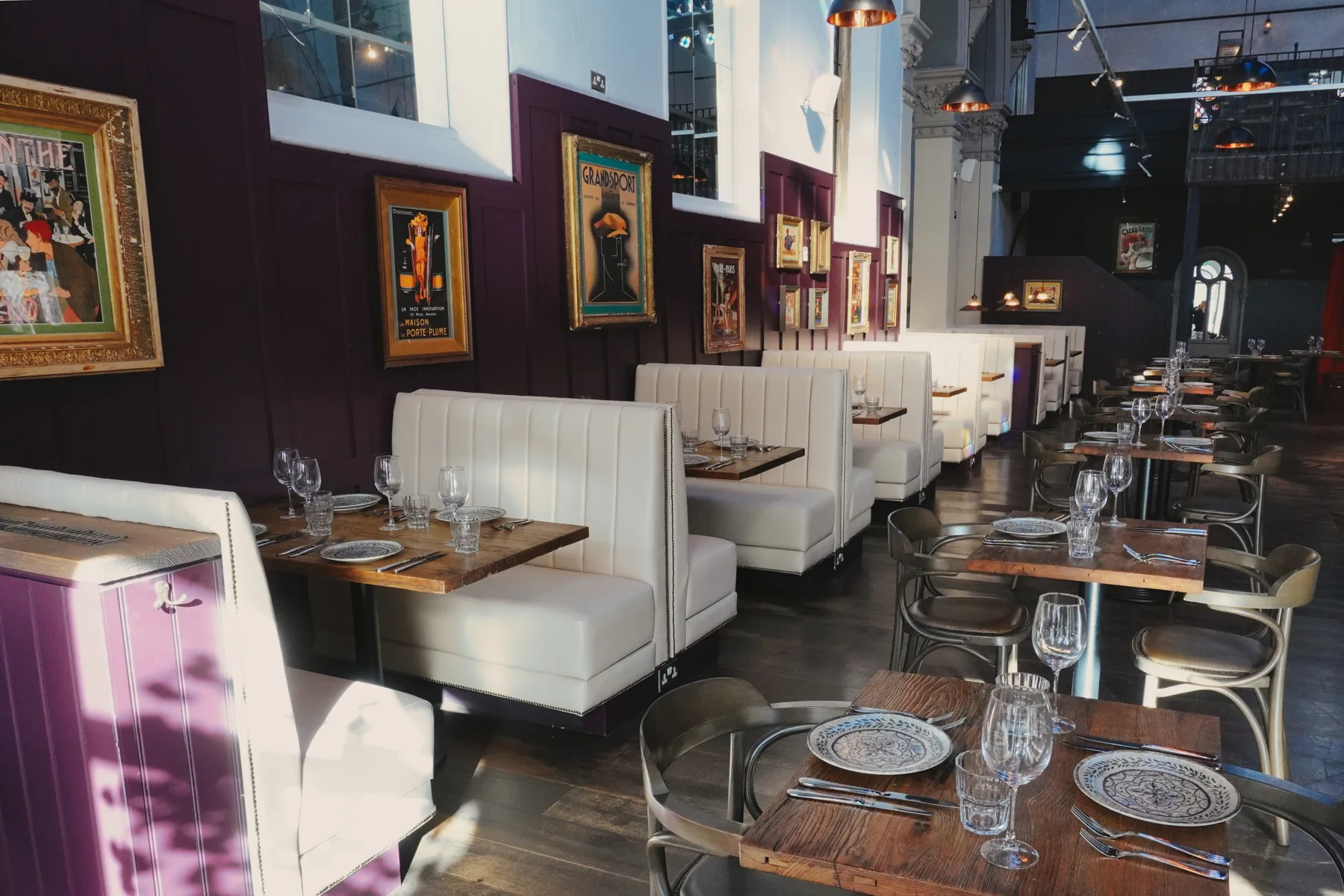 Sunlit tables and cream seating along Lukaâ€™s plum-panelled dining room