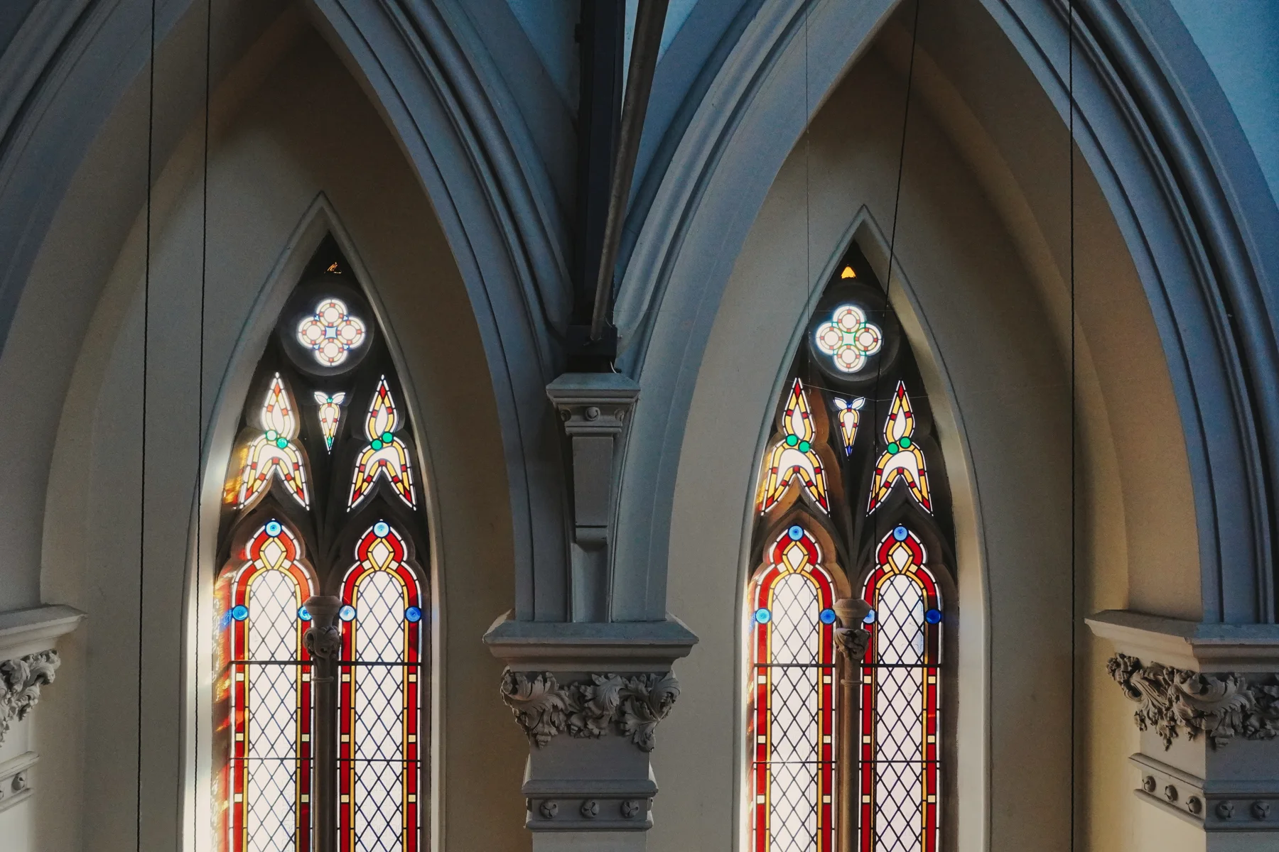 Twin stained-glass windows framed by carved stone arches