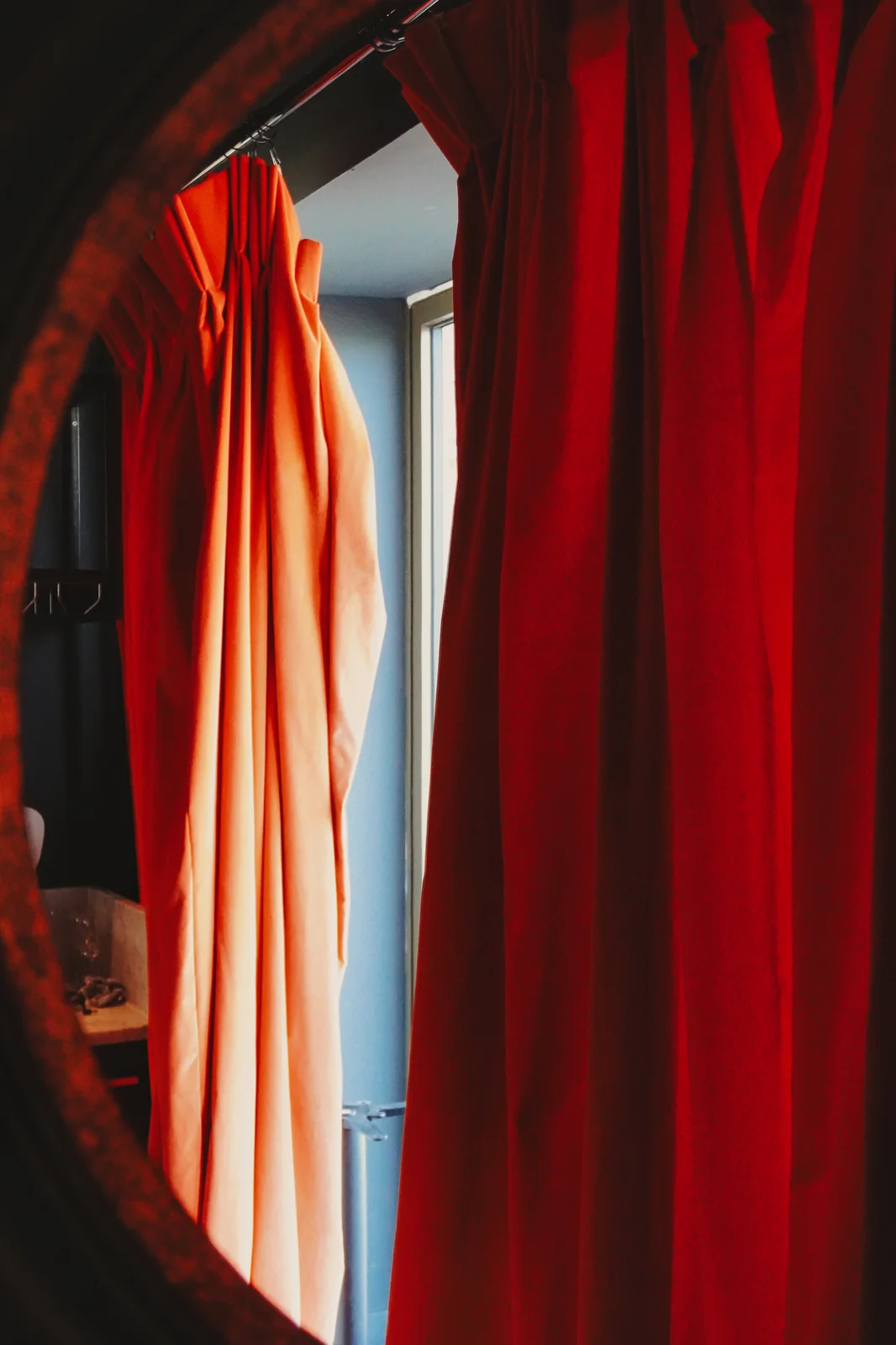 Warm red curtains reflected in a round mirror