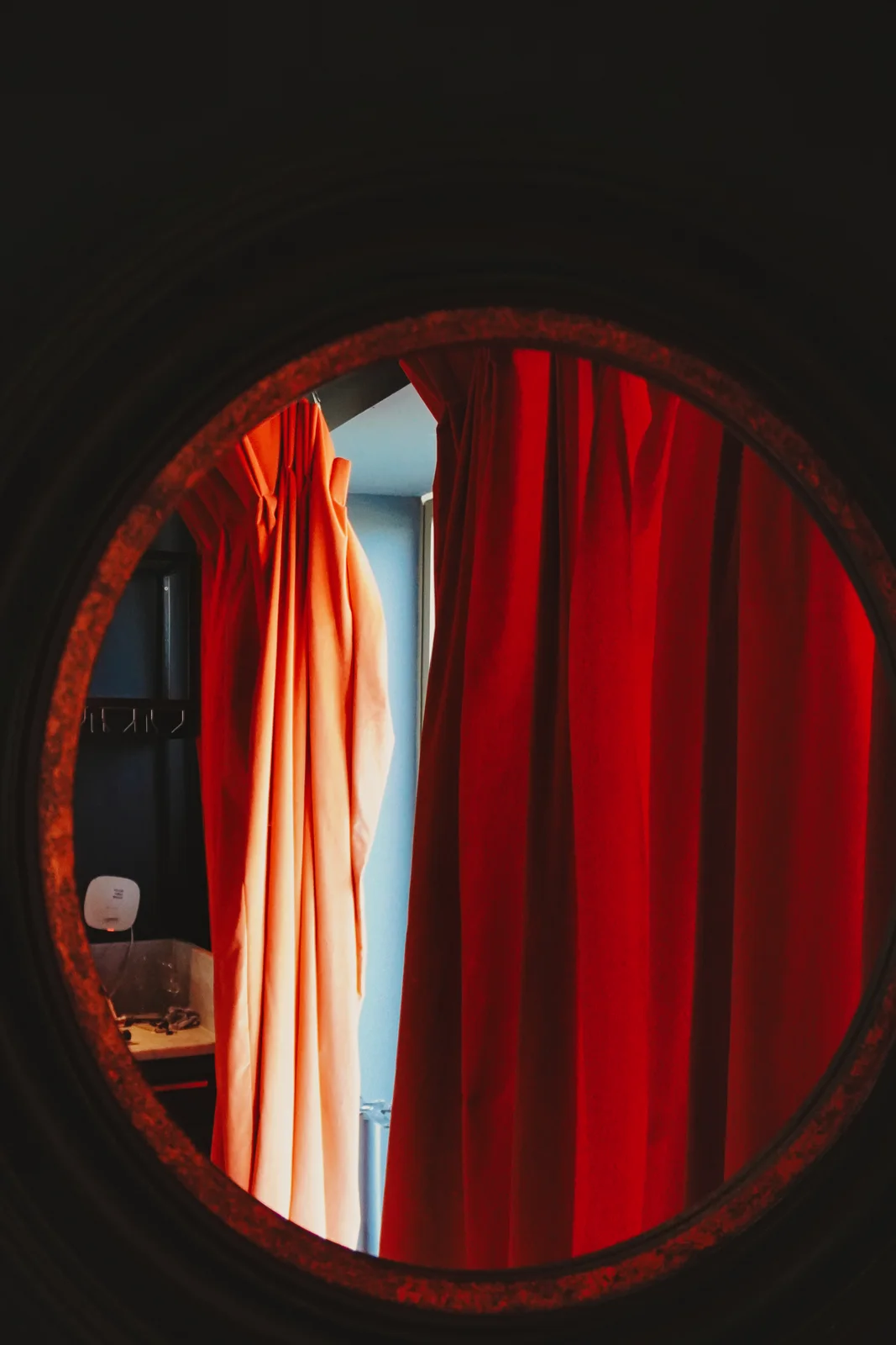 Warm red curtains reflected in a round mirror