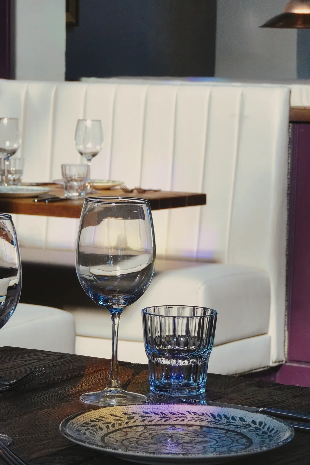 Glassware and place settings beside cream seating